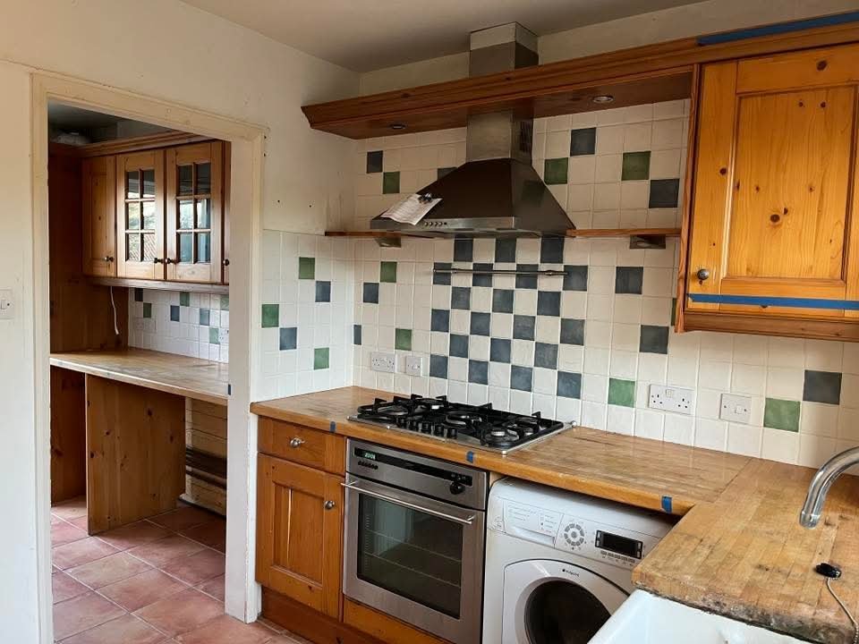 Old kitchen before renovation with outdated cabinets and worn surfaces